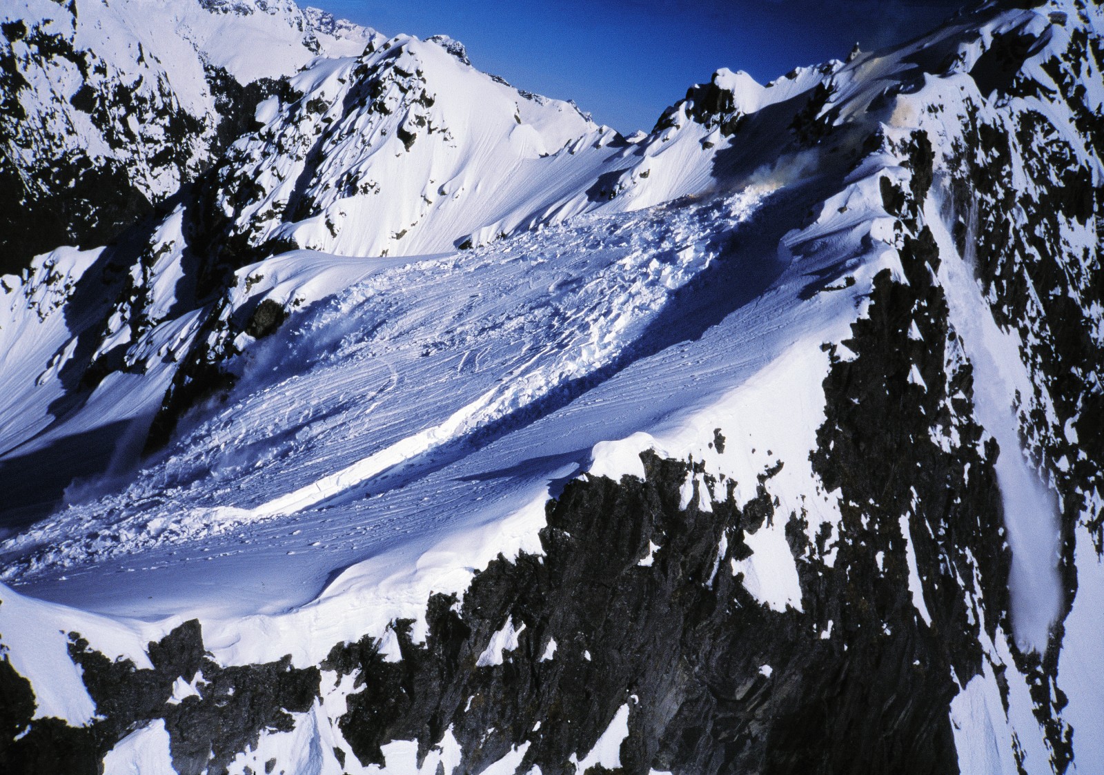 In the main image, smoke from a detonated "bomb" (visible at top right) and an ominous crack indicate that this snowfield has been given a nudge and is about to take off down the mountain.