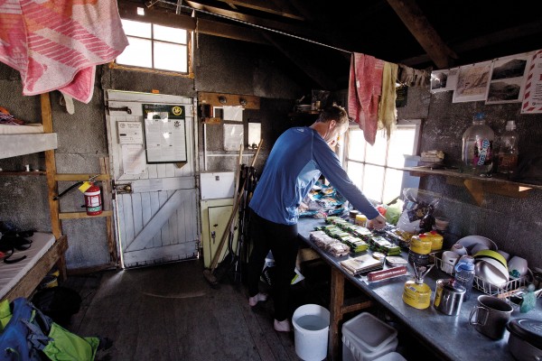 haast_kitchen Godley Hut has been a safe haven for climbers since it was built by members of the New Zealand Alpine Club in 1934. Previously, the Mount Cook Tourist Company managed all the huts in what was then known as Tasman Park, and amateur climbers that didn’t utilise the company’s guides were regarded with a little disdain. The NZAC hut, just outside of reserved lands, was badly undermined by the Godley River in 1955 and subsequently dismantled and shifted 300 m to its present site.