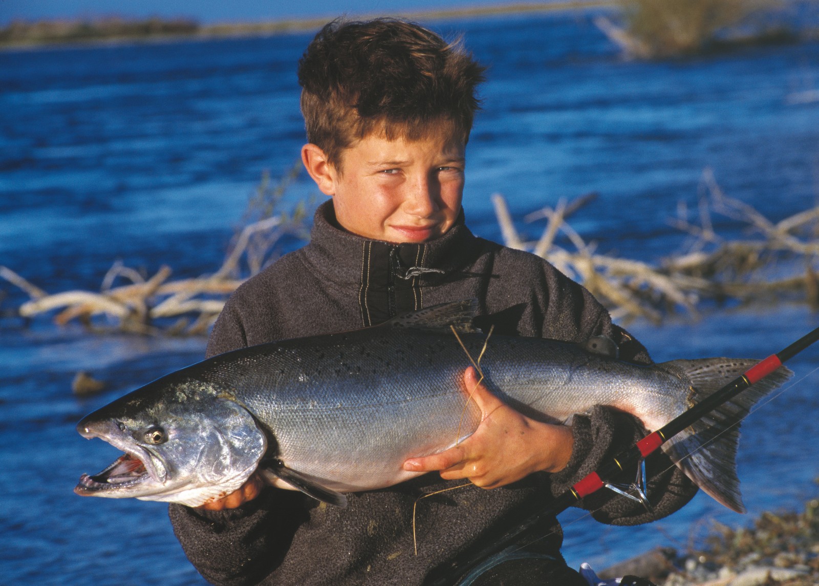 51_Waitaki_01 Historically prized for its eel, whitebait, lamprey and mullet fisheries, the Waitaki is now a Mecca for trout and salmon anglers. The author's son Jeremy, here displaying a 6 kg salmon he landed from the Waitaki, caught his first trout at the age of three. The river is one of relatively few in the country to host thriving populations of both trout and salmon.