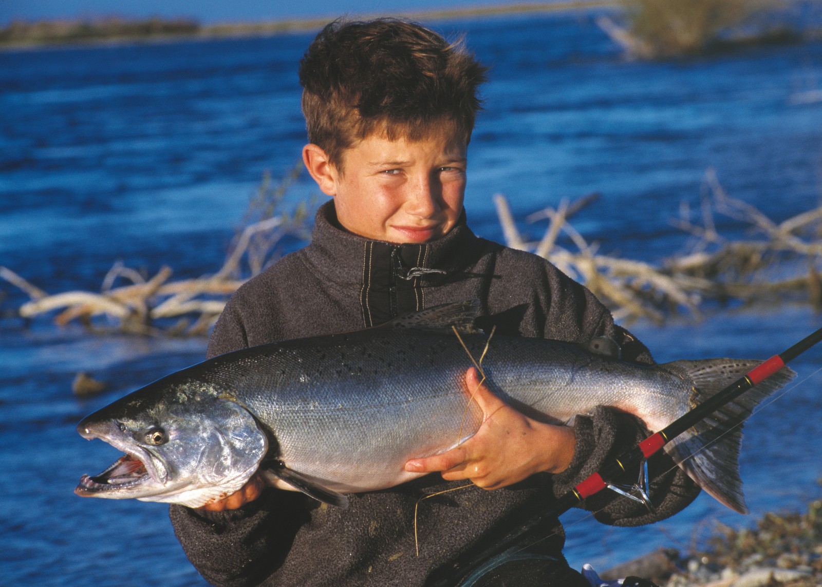 Historically prized for its eel, whitebait, lamprey and mullet fisheries, the Waitaki is now a Mecca for trout and salmon anglers. The author's son Jeremy, here displaying a 6 kg salmon he landed from the Waitaki, caught his first trout at the age of three. The river is one of relatively few in the country to host thriving populations of both trout and salmon.