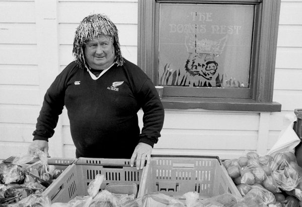 81_Grahamstown_11 Further along Pollen Street, a produce vendor enters into the spirit of market day, selling fruit & vege’s from his stall garbed in a tinsel wig.
